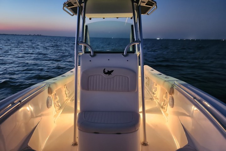 center console fishing boat rental in sarasota bay with lights on inside boat at dusk