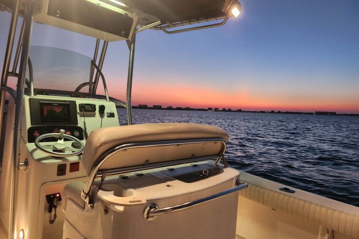 mako center console fishing boat rental in sarasota bay at night with sunset and interior boat lights on