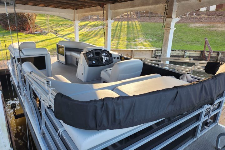 An up-close view of a well-appointed pontoon boat interior, complete with plush seating, tables, and panoramic windows
