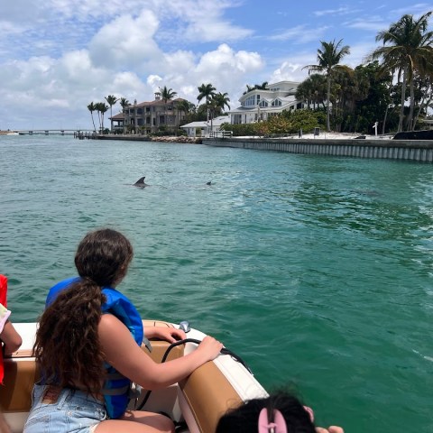 a group of young children sitting next to a body of water