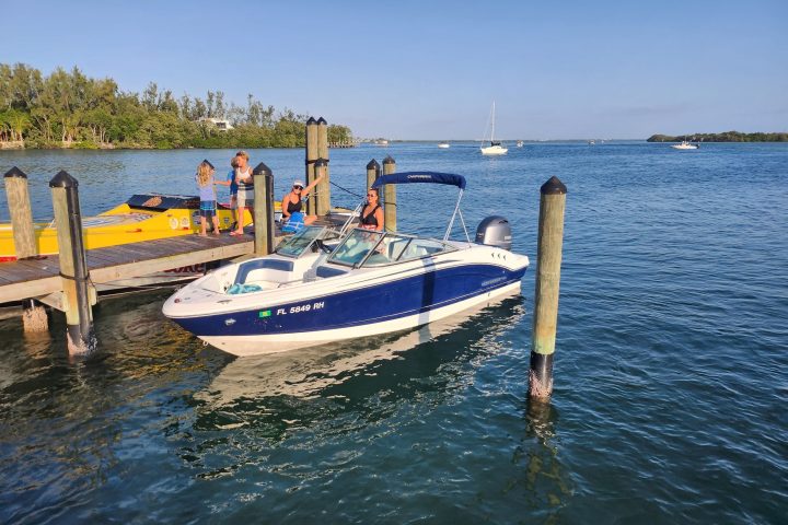A 21-foot Chaparral Bow Rider boat rental parked in Sarasota, FL, floating on calm, turquoise waters at the dock
