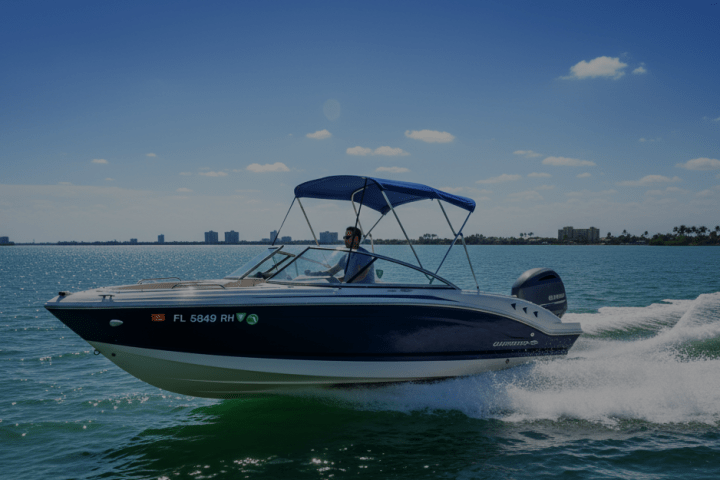 A speedboat on water with a person driving under a clear blue sky.