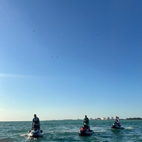 a group of people flying kites near the water