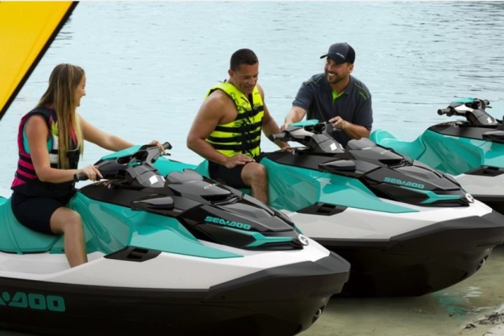 two people sitting on the jet skis in the water