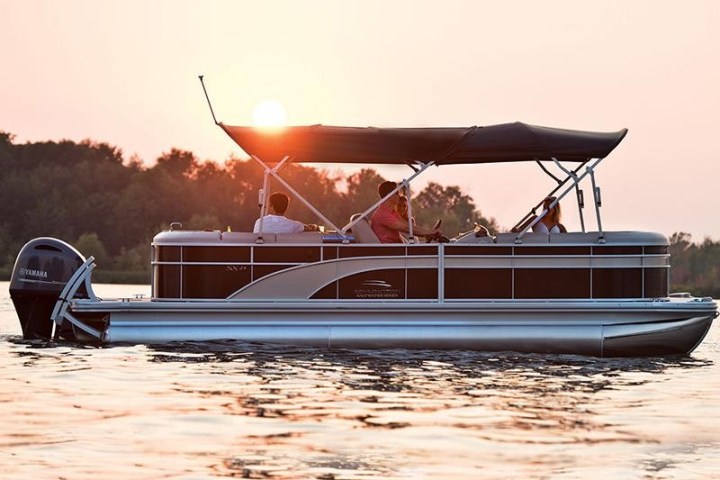 pontoon boat rental gliding through the calm waters of Sarasota Bay during a colorful sunset.
