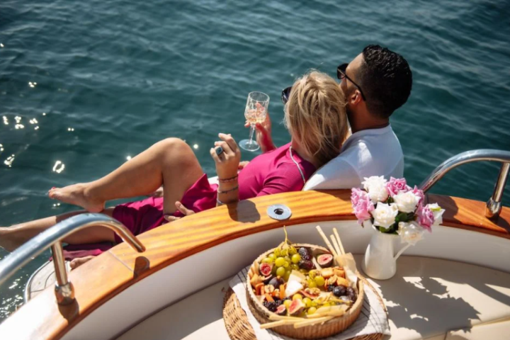 people sitting at a table with food and wine enjoying a date on a boat rental