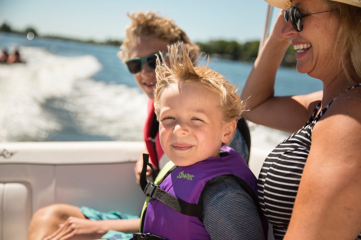 a woman sitting on a boat with her 2 sons for a mothers day boat rental
