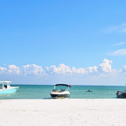 a boat sitting on top of a sandy beach next to the ocean