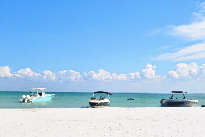 a boat sitting on top of a sandy beach next to the ocean