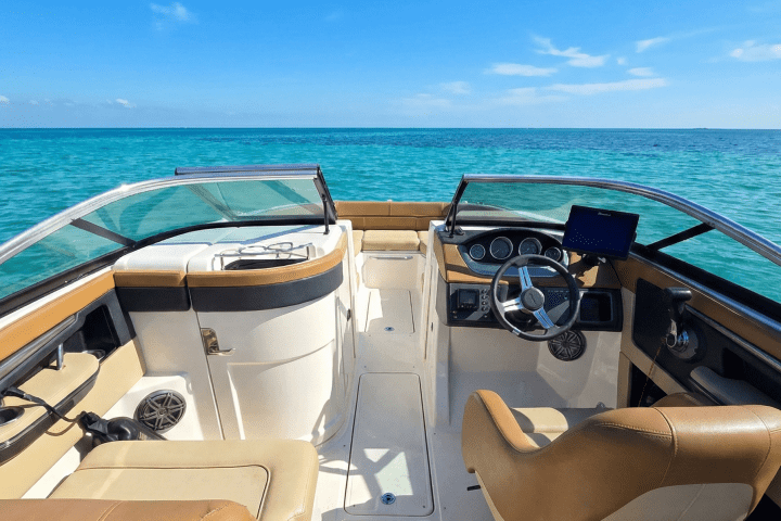 View from a boat interior with tan seats and blue ocean in the background.